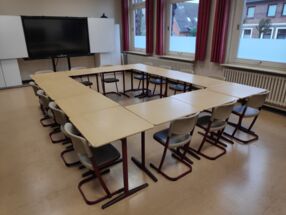 Im Quadrat aufgebaute Tische und Stühle in einem Klassenraum