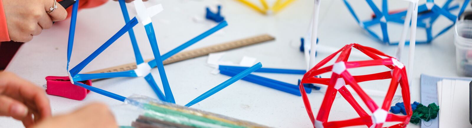 Kinder basteln mit farbigem Papier vieleckige Boxen.