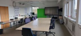 Foto in der Medienwerkstatt in Kronshagen. Konferenztisch mit Stühlen, Greenscreen und digitales Board im Hintergrund
