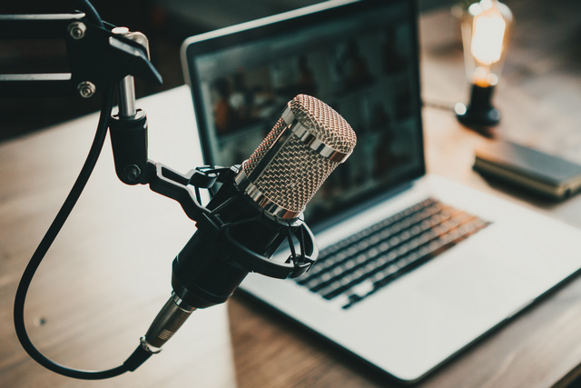 Heimstudio-Podcast-Interieur. Mikrofon, Laptop und On-Air-Lampe auf dem Tisch.