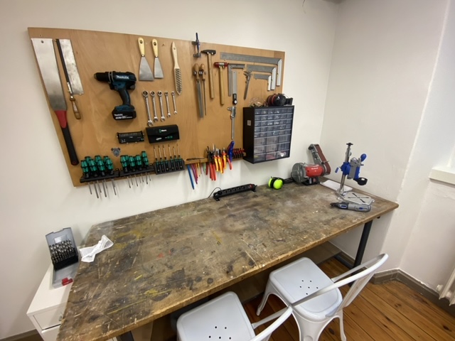 Blick auf de Holzbearbeitungsbereich mit Werktisch und an der Wand aufgehängten Werkzeugen